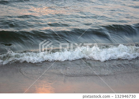 Sea wave washing sandy beach at sunset 132946730