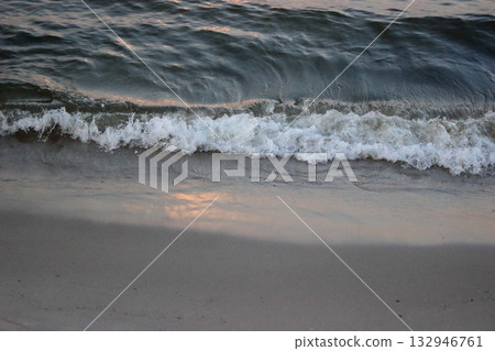 Sea wave washing sandy beach at sunset 132946761