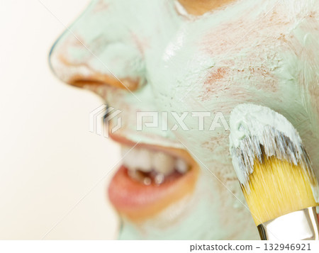 Female applying green mud facial mask Female applying green mud facial mask 132946921