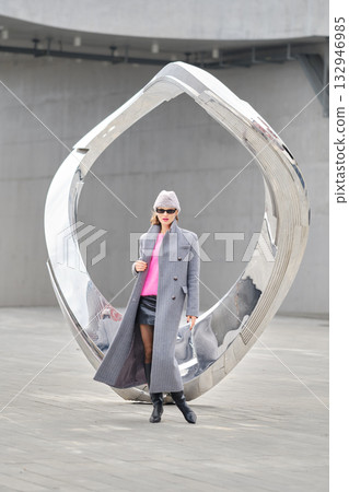Urban street style model poses confidently near a modern sculpture in a vibrant cityscape Urban street style model poses confidently near a modern sculpture in a vibrant cityscape 132946985