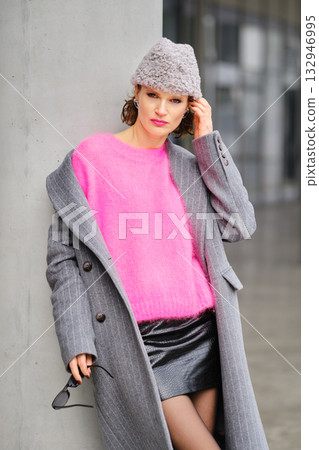 Urban street style highlights vibrant pink sweater and chic gray coat against modern backdrop 132946995