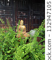 Terracotta Buddha statue among green plants 132947105
