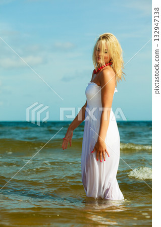 Blonde woman wearing dress walking in water 132947138