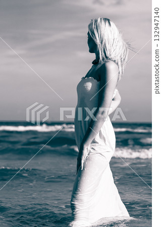 Blonde woman wearing dress walking in water 132947140