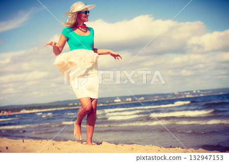 Blonde woman wearing dress walking on beach 132947153