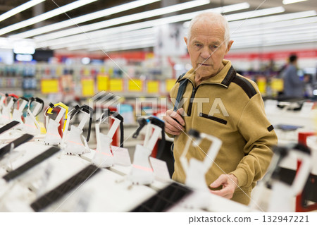 elderly man examines smart watch in showroom of electronics store elderly man examines smart watch in showroom of electronics store 132947221