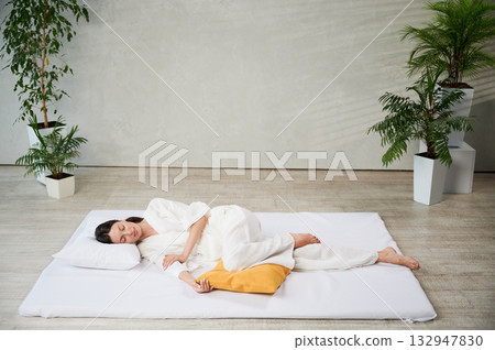 Beautiful woman relaxing after Thai massage, lying on mat with closed eyes. Beautiful woman relaxing after Thai massage, lying on mat with closed eyes. 132947830