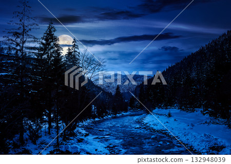 freezing river winding among coniferous forest at night. snow on the ground in countryside valley in full moon light. background for investment or abstract concepts freezing river winding among coniferous forest at night. snow on the ground in countryside valley in full moon light. background for investment or abstract concepts 132948039