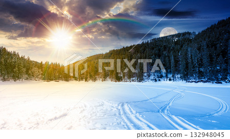 winter landscape with snow covered ground. day and night time change concept. frozen lake among spruce forest with sun and moon. panoramic view of winter wonderland. duality and transition template winter landscape with snow covered ground. day and night time change concept. frozen lake among spruce forest with sun and moon. panoramic view of winter wonderland. duality and transition template 132948045