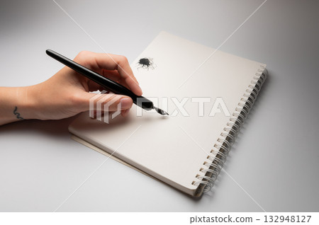 Calligraphy training. A fountain pen in someone's hands, stained with ink. Ink blot, pen on a white background, close-up Calligraphy training. A fountain pen in someone's hands, stained with ink. Ink blot, pen on a white background, close-up 132948127