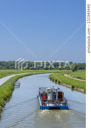 Vnorovy canal boat cruising along rural waterway 132948448