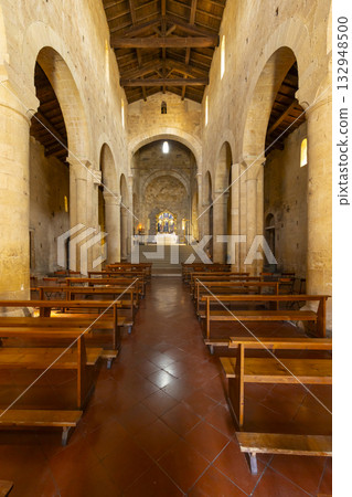 Church interior with wooden pews and stone arches in Monteriggioni 132948500