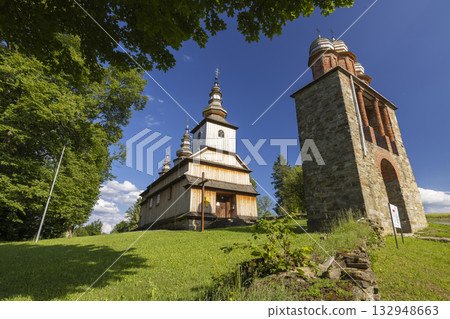 Historic wooden church and bell tower on a sunny day in Binarowa, Poland 132948663