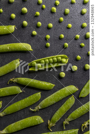 Fresh green peas, pods, and pattern on black surface Fresh green peas, pods, and pattern on black surface 132948665
