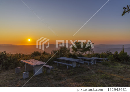 Picnic area tables on hill with sunset mountain view 132948681
