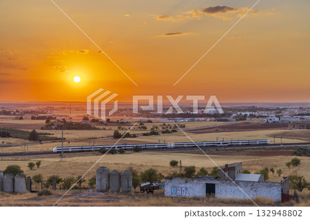 High speed train traveling Alcazar de San Juan at sunset High speed train traveling Alcazar de San Juan at sunset 132948802