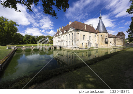 Chateau de Commarin reflecting in its moat under a blue sky Chateau de Commarin reflecting in its moat under a blue sky 132948871