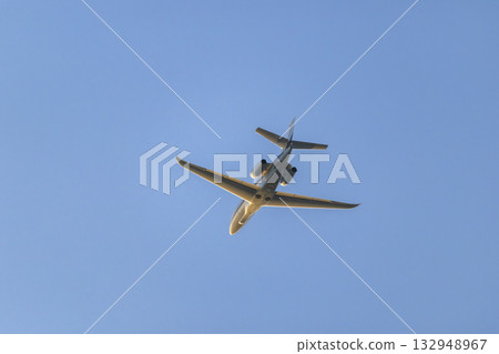 Private jet aircraft flying overhead in blue sky Private jet aircraft flying overhead in blue sky 132948967