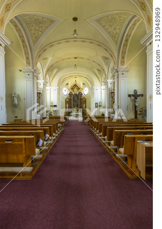 Church interior with wooden pews and religious decorations in Vnorovy 132948969