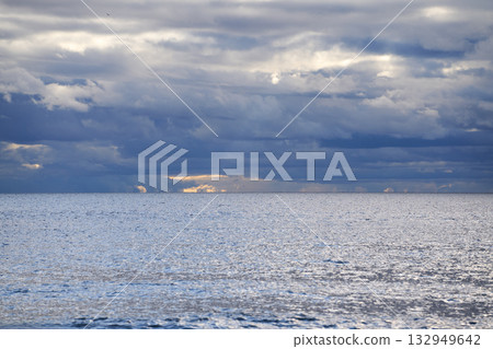 Dramatic cloudy sky over calm sea surface at horizon in daylight. Dramatic cloudy sky over calm sea surface at horizon in daylight. 132949642