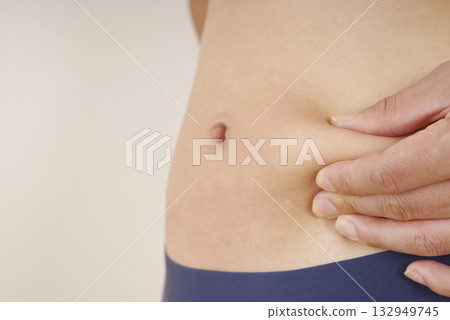 一位中年男子用手指捏著腹部的皮下脂肪 一位中年男子用手指捏著腹部的皮下脂肪 132949745