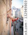 Close-up of female legs with red shoes of high heels. The woman is raising her feet through the window 132949869
