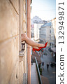 Close-up of female legs with red shoes of high heels. The woman is raising her feet through the window 132949871