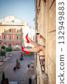 Close-up of female legs with red shoes of high heels. The woman is raising her feet through the window 132949883