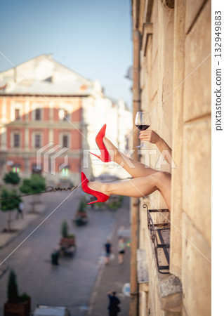 Close-up of female legs with red shoes of high heels. The woman is raising her feet through the window Close-up of female legs with red shoes of high heels. The woman is raising her feet through the window 132949883