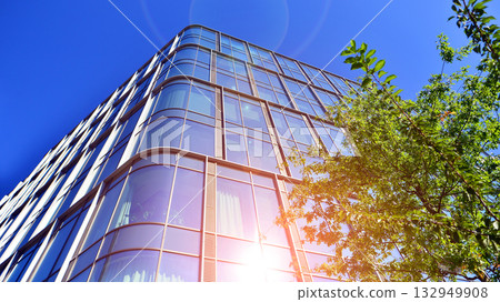 Modern luxury office building.The structure features a glass and concrete walls, showcasing contemporary architecture. The green surroundings of office buildings. Trees and shrubs in the city. Modern luxury office building.The structure features a glass and concrete walls, showcasing contemporary architecture. The green surroundings of office buildings. Trees and shrubs in the city. 132949908
