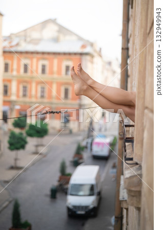 Close-up of female legs with red shoes of high heels. The woman is raising her feet through the window 132949943