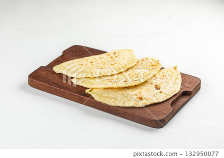 Portion of qutab flatbreads on wooden board 132950077