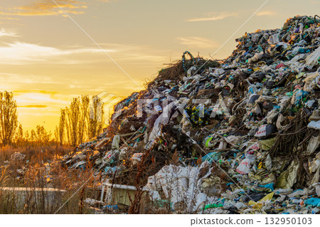 A large landfill site filled with garbage and waste is highlighted against a beautiful sunset, showing pollution's effects on nature A large landfill site filled with garbage and waste is highlighted against a beautiful sunset, showing pollution's effects on nature 132950103