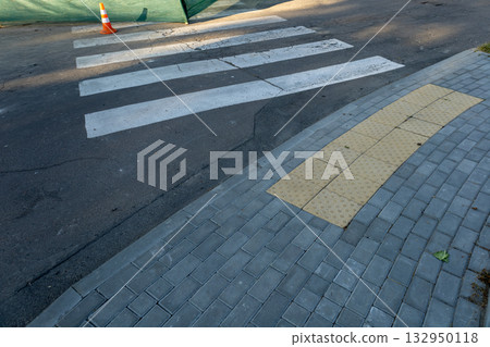Fresh white stripes mark the pedestrian crosswalk beside a road, highlighting safety as construction work continues in the background Fresh white stripes mark the pedestrian crosswalk beside a road, highlighting safety as construction work continues in the background 132950118