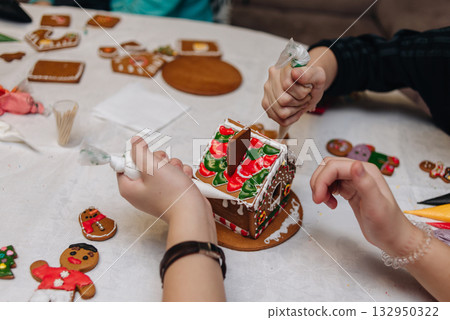 Children decorating gingerbread house with icing and candy, Christmas fun activity 132950322