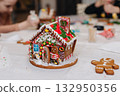 Children decorating gingerbread house with icing and candy, Christmas fun activity 132950356