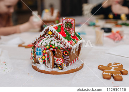 Children decorating gingerbread house with icing and candy, Christmas fun activity 132950356