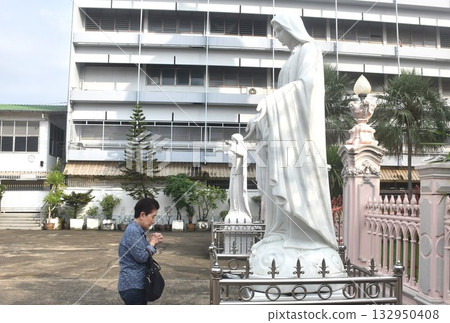 Asian elder woman standing and pay respect front of Santa Cruz church ancient community of Portuguese Christian travel location in Thailand  132950408