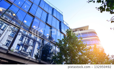 Modern luxury office building.The structure features a glass and concrete walls, showcasing contemporary architecture. The green surroundings of office buildings. Trees and shrubs in the city. 132950492