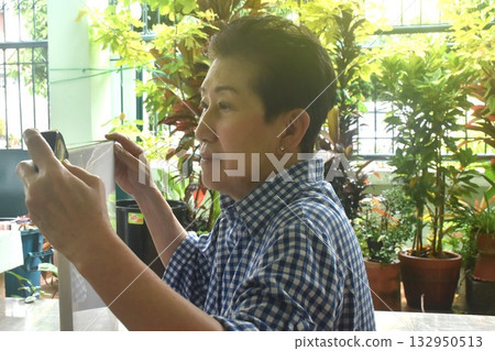 Asain elder woman measuring canvas picture frame in home front yard 132950513