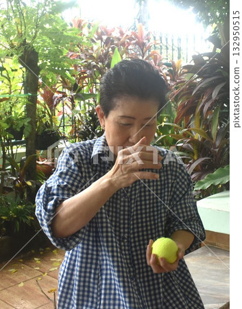 Asain elder woman thrown and dropping yellow tennis ball for exercise in home front yard 132950515