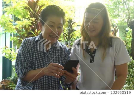 Asian elder woman and daughter to checking mobile phone in front of home 132950519