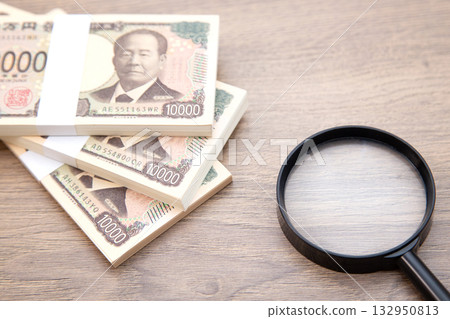 A stack of bills and a magnifying glass A stack of bills and a magnifying glass 132950813