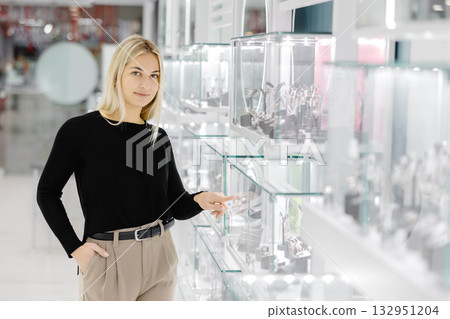 Woman choosing jewelry in a store pointing at glass display Woman choosing jewelry in a store pointing at glass display 132951204