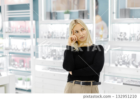 Pensive customer choosing jewelry in a shop Pensive customer choosing jewelry in a shop 132951210