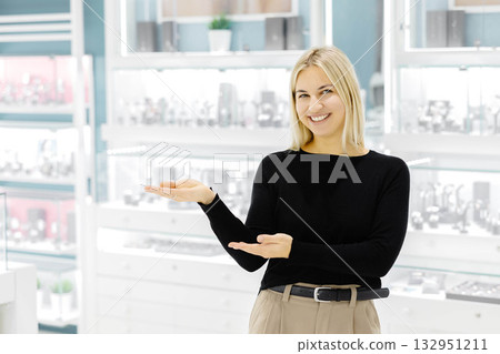 Smiling shop assistant showing jewelry in a jewelry store Smiling shop assistant showing jewelry in a jewelry store 132951211