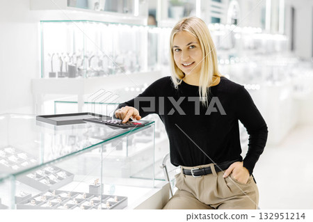 Saleswoman calculating price using calculator in jewelry shop 132951214