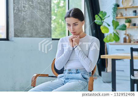 Sad upset teenager girl sitting at home in living room 132952406