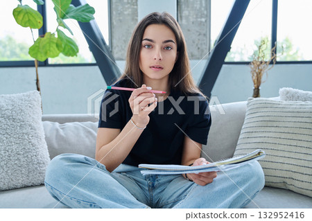 Webcam view of teenage girl student with textbook studying online remotely, video lesson 132952416