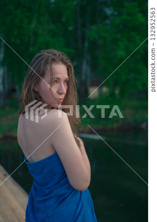 Woman Wrapped in Towel Relaxing by Lake at Sunset Woman Wrapped in Towel Relaxing by Lake at Sunset 132952563